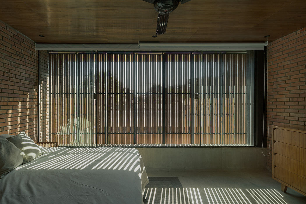 Modern bedroom with brick walls, wooden slats window, and striped bedding.