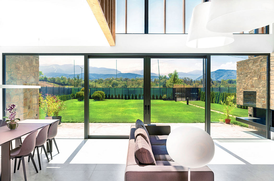 Modern living room with large windows overlooking a garden and mountains.
