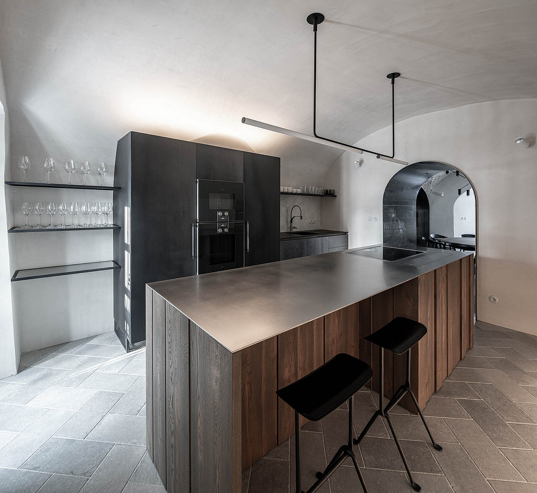 Modern kitchen with a central island, black stools, and minimalist lighting.