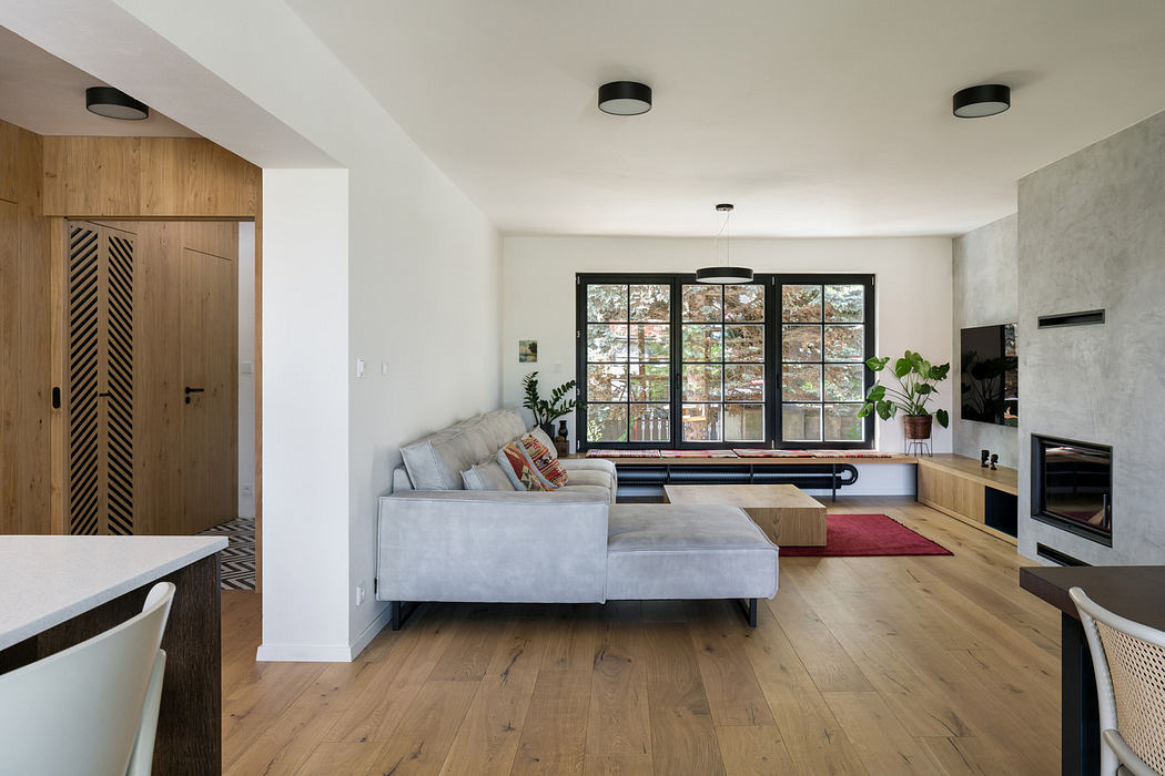 Contemporary living room with wooden floors, large windows, and a minimalist design.