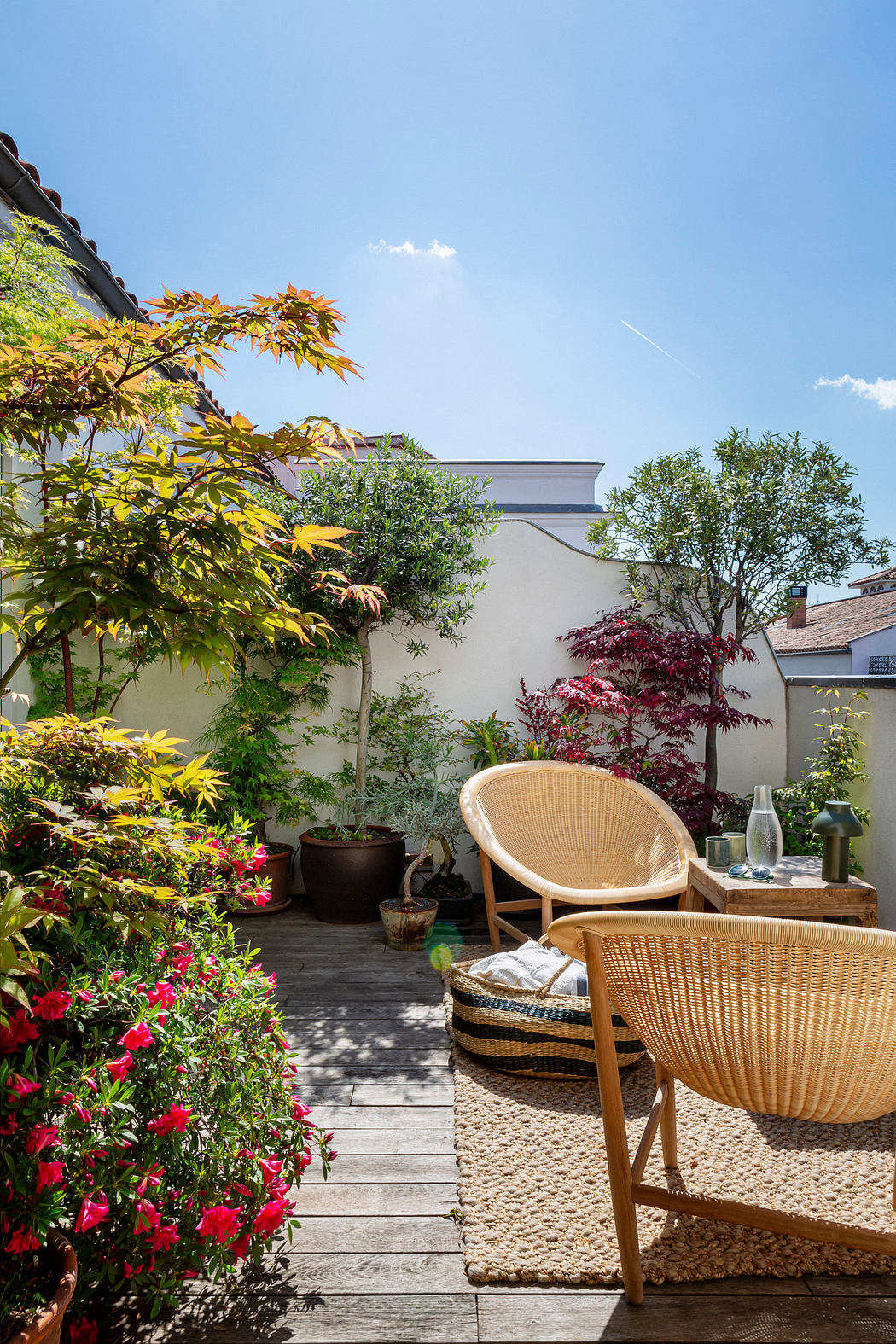 Sunny patio with a wicker chair, wooden deck, and greenery.