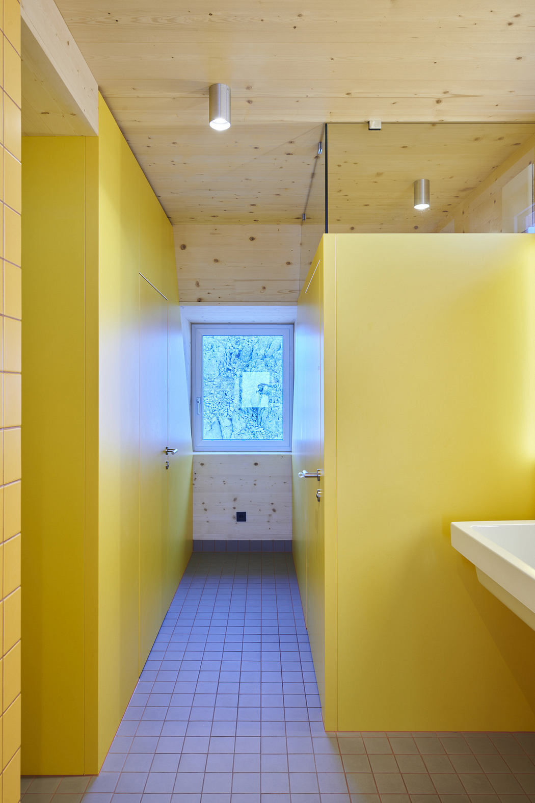 Bright yellow bathroom with wooden ceiling and minimalist design.