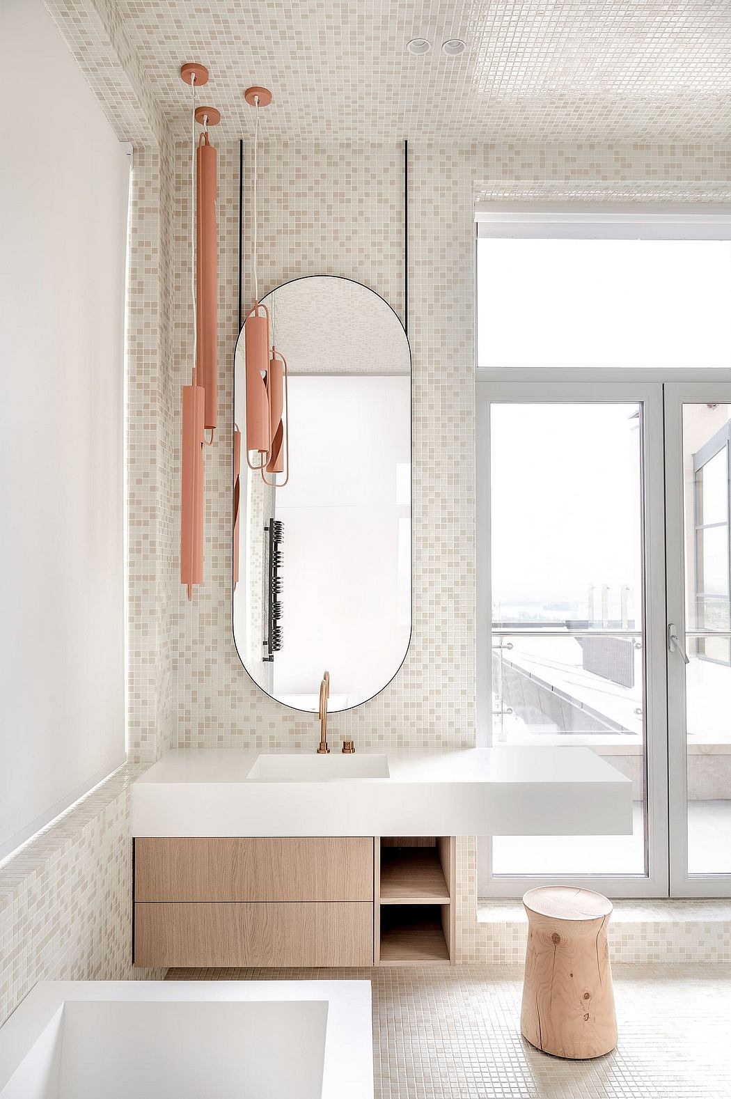 Minimalist bathroom with pale wood vanity and mosaic tile walls.