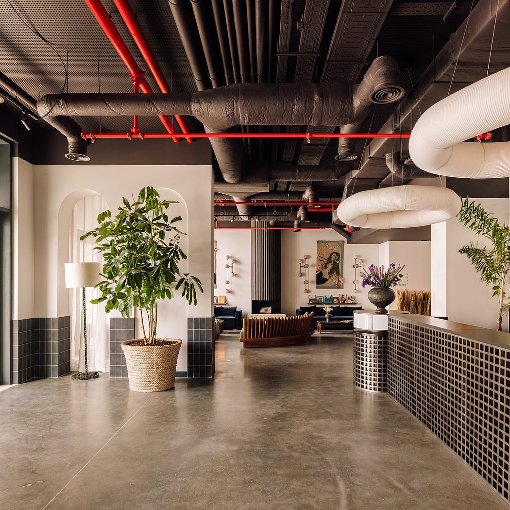 Modern office interior with exposed red pipes, ductwork, and stylish furniture.