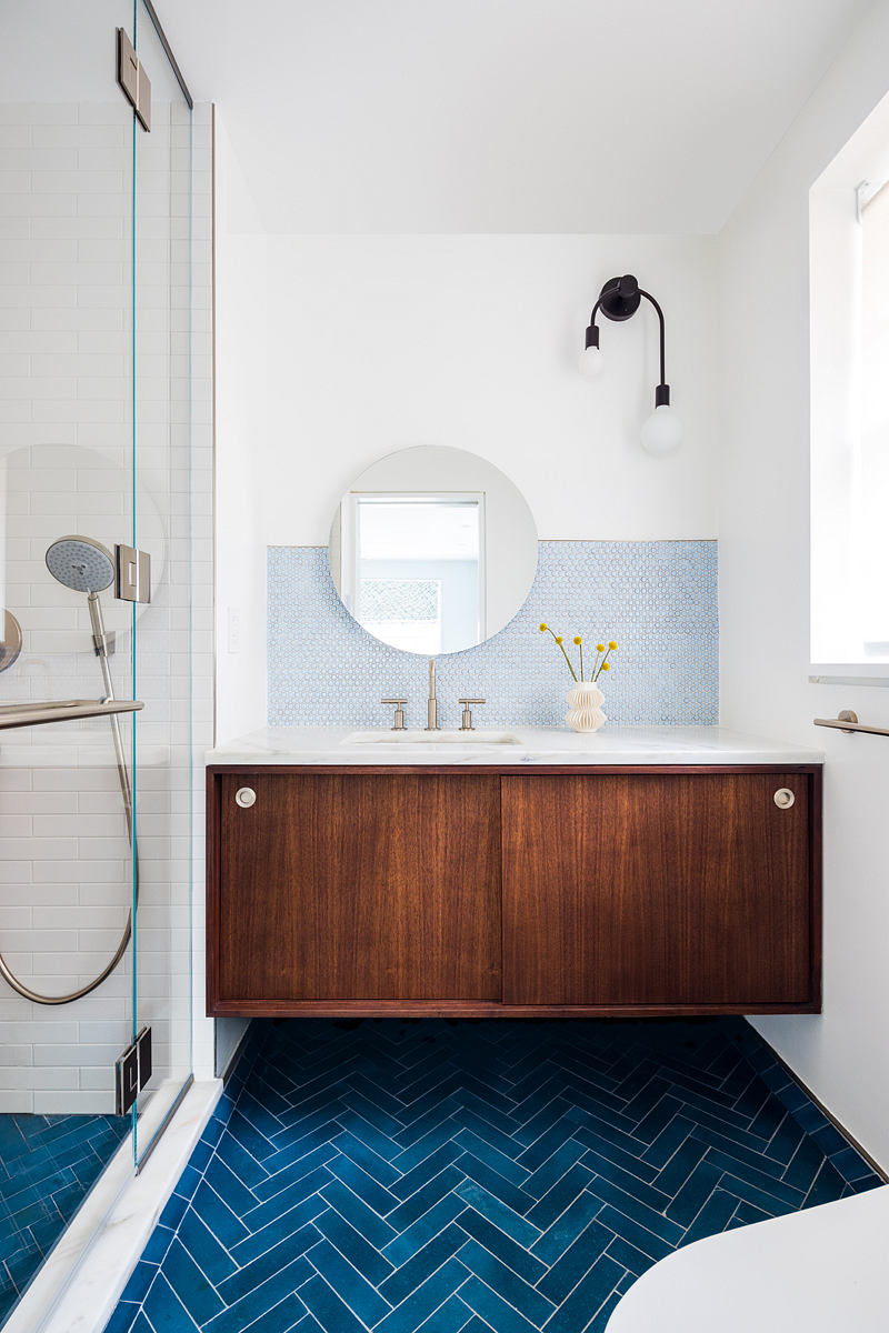 Contemporary bathroom with blue herringbone floor tiles and wooden vanity.