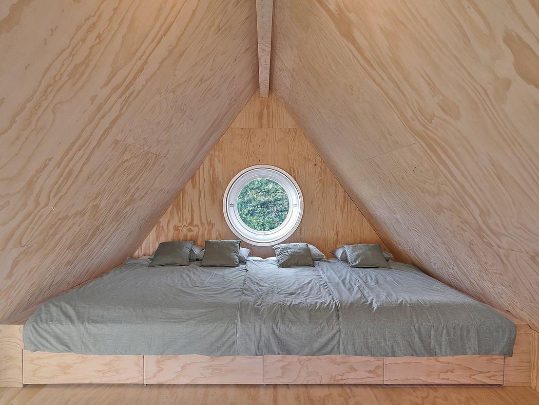 A cozy attic bedroom with a round window and wooden walls.