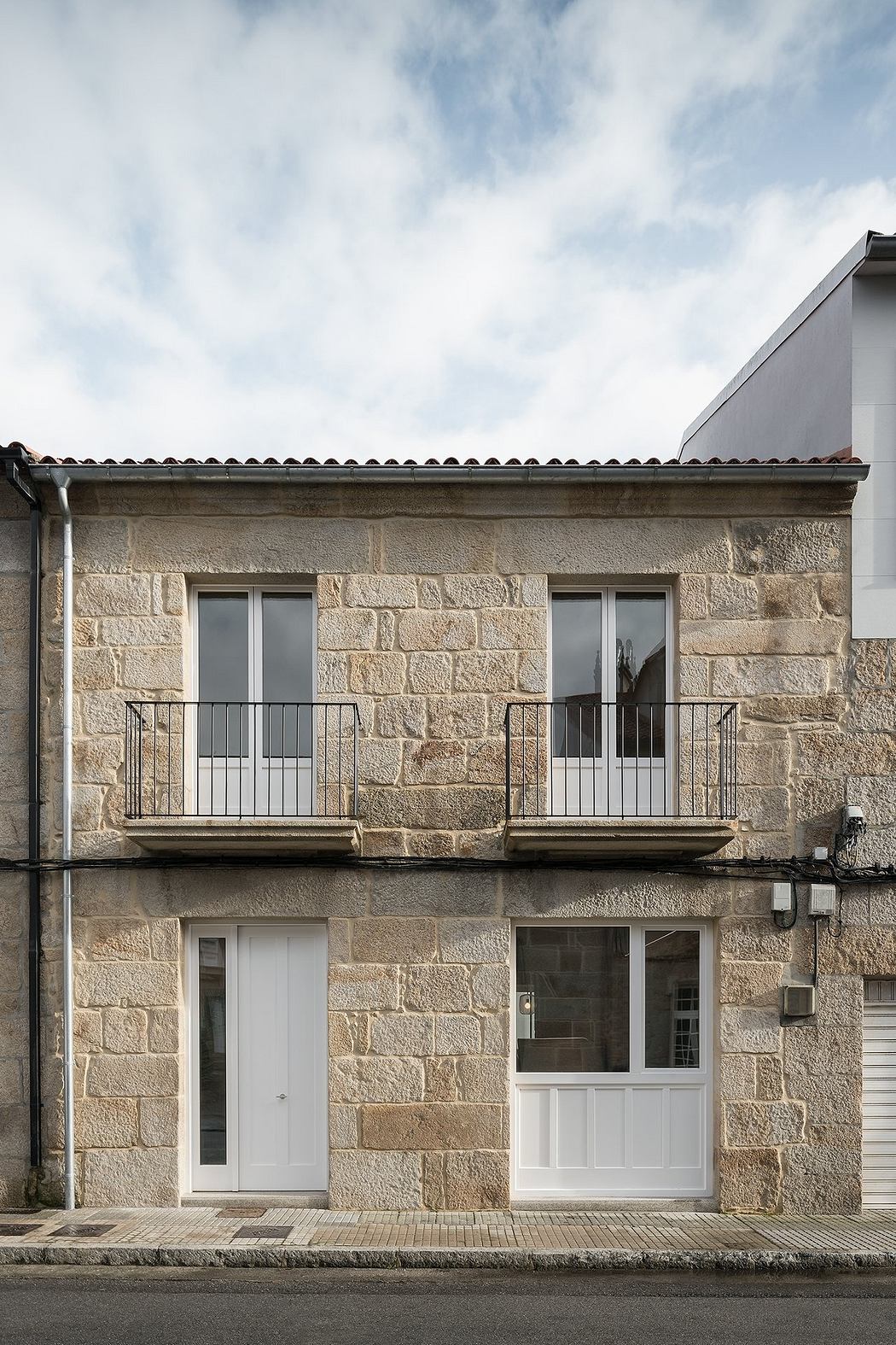 Two-story stone facade building with balconies and white doors.