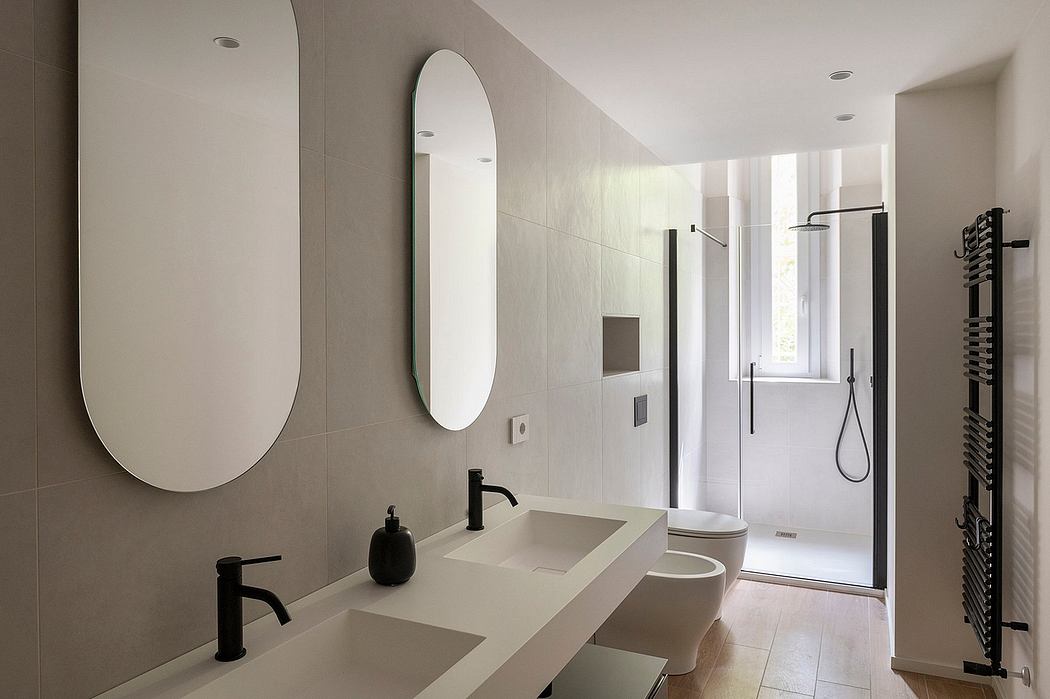 Sleek bathroom with dual oval mirrors and minimalist fixtures.