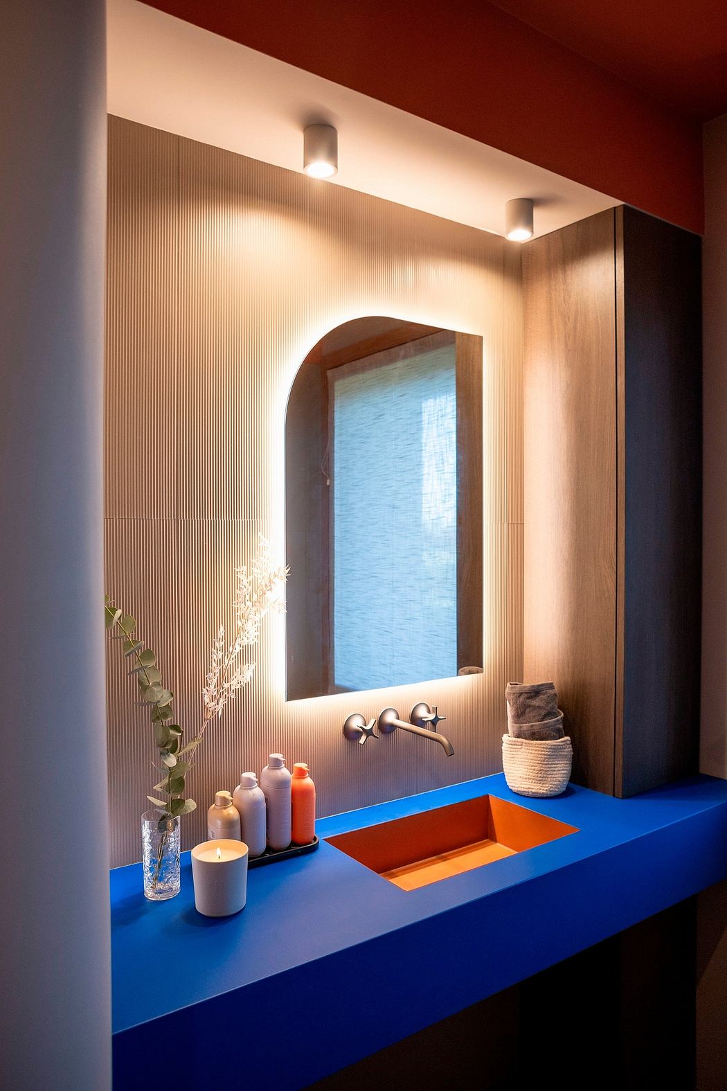 Modern bathroom vanity with mirror, blue countertop, and decorative items.