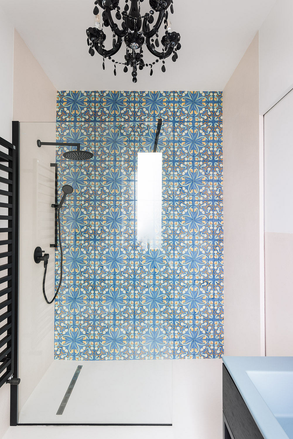 Elegant bathroom with blue patterned tiles and black chandelier.