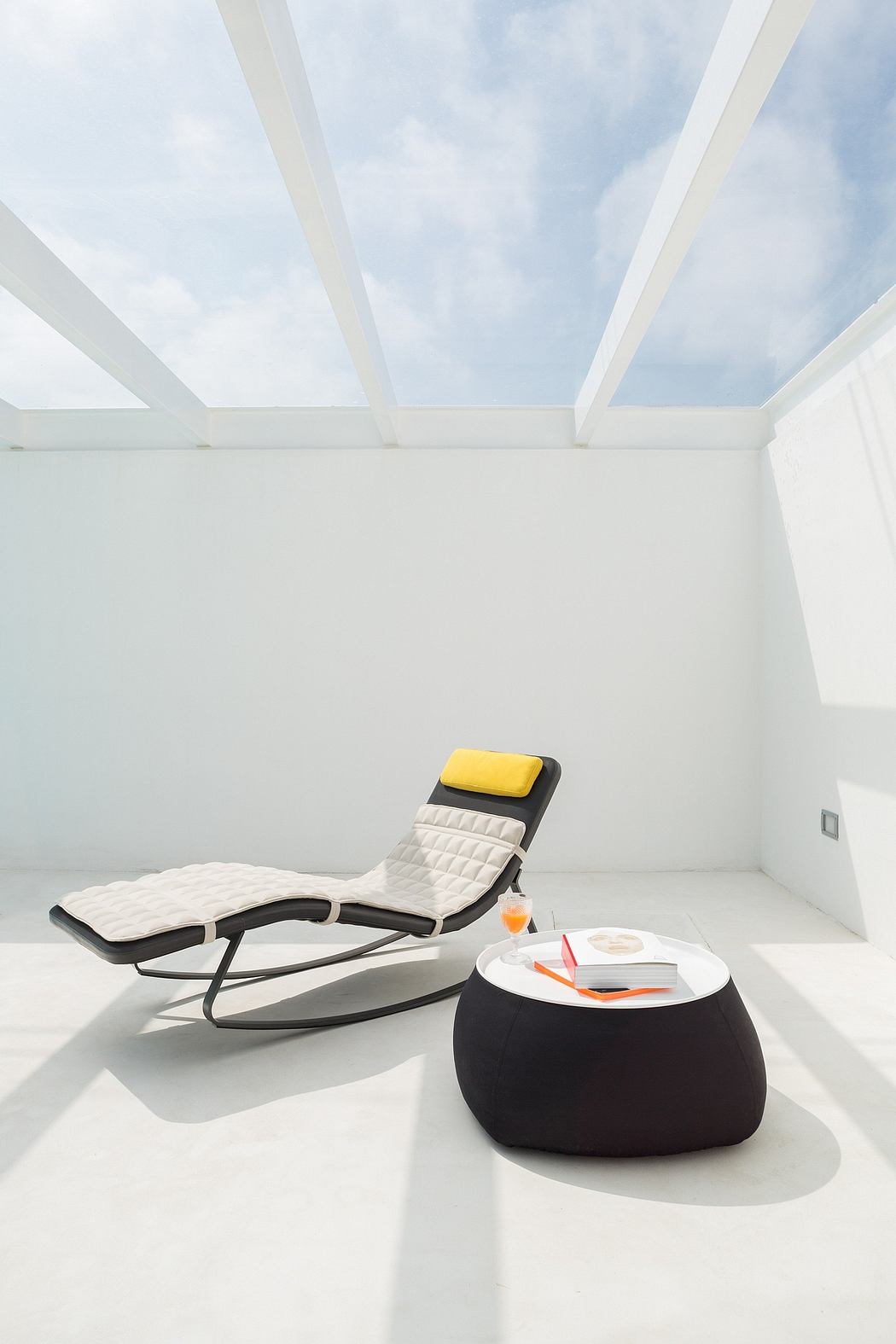 Contemporary white rooftop patio with lounge chair and skylight.