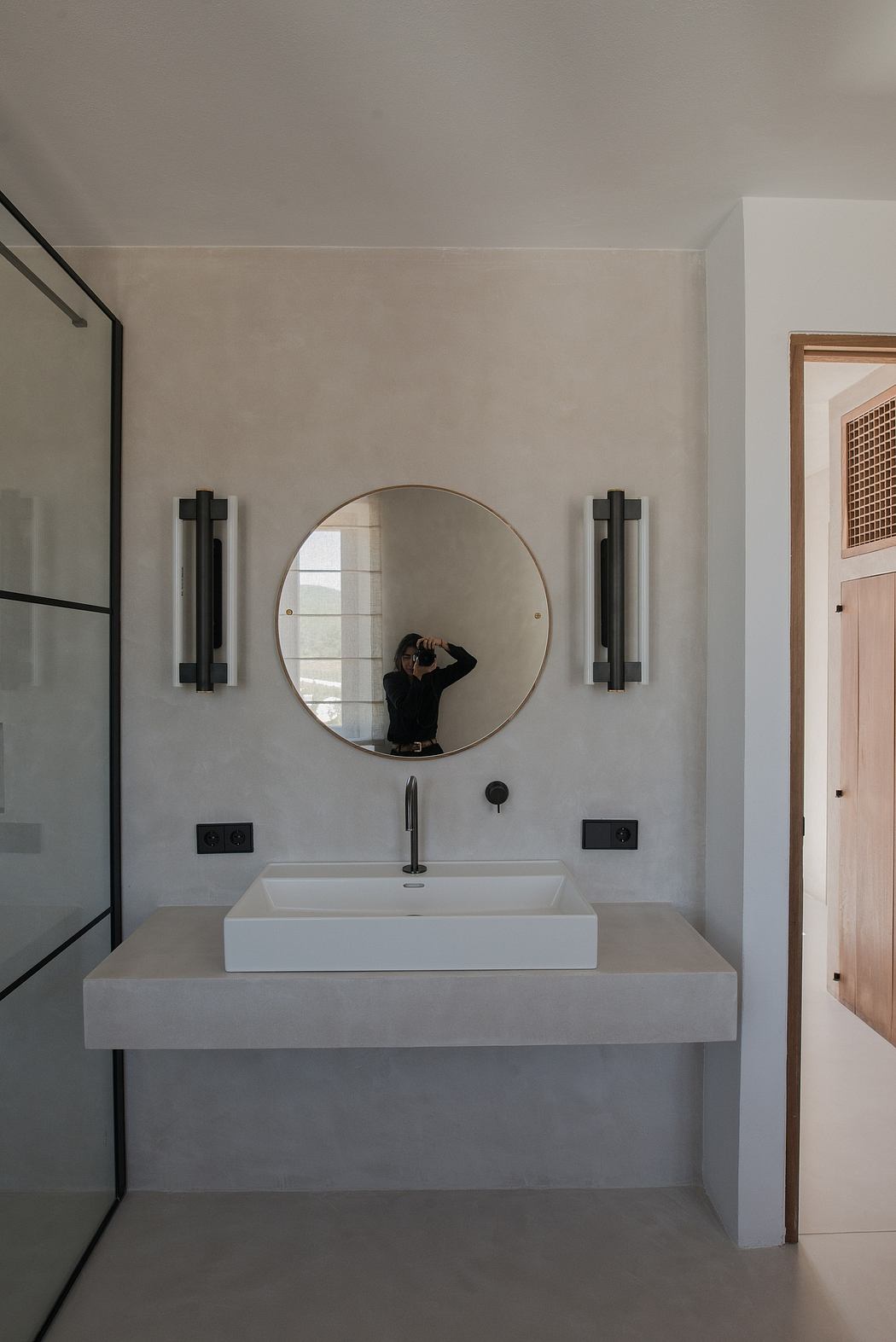 Modern bathroom with a circular mirror and a minimalist white sink.