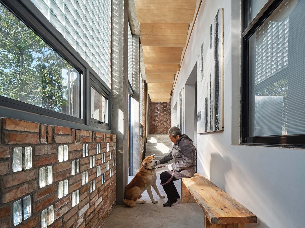 Modern hallway with brick accent wall, bench seating, and a person petting a