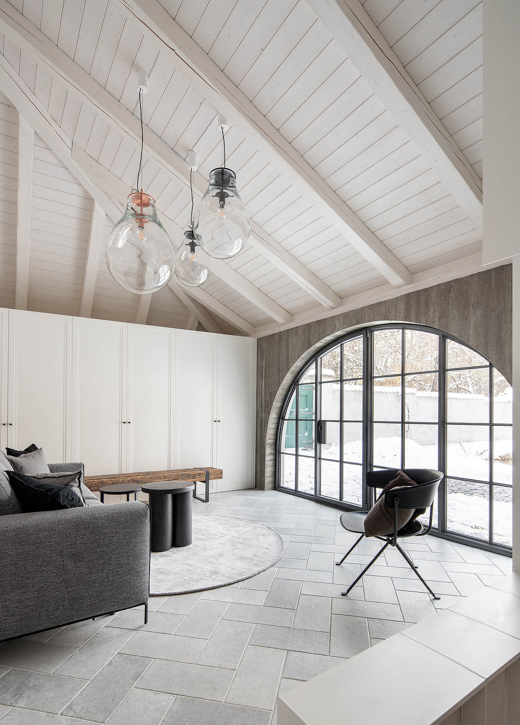 Contemporary room with vaulted ceiling, large arched window, and unique pendant