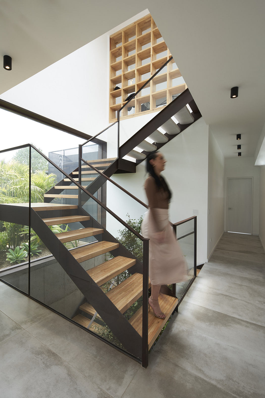 Modern staircase with wooden steps, metal railings, and a blurred person descending.