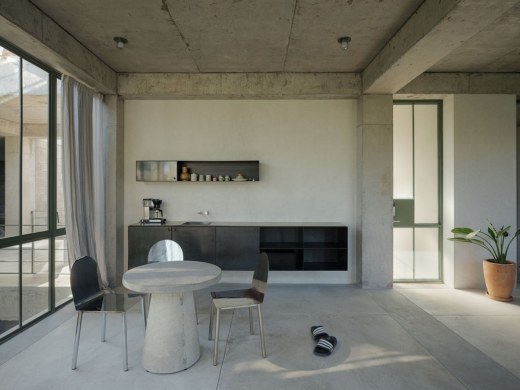 Minimalist interior with concrete walls, sleek kitchen, and round table.