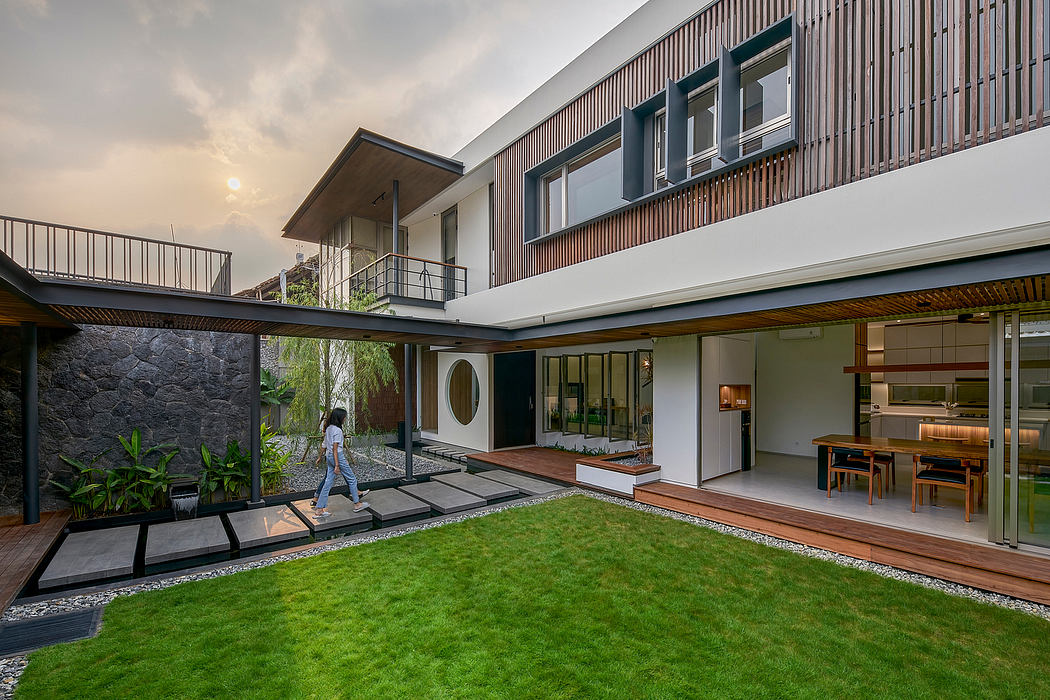 Modern house exterior with garden and walking person.