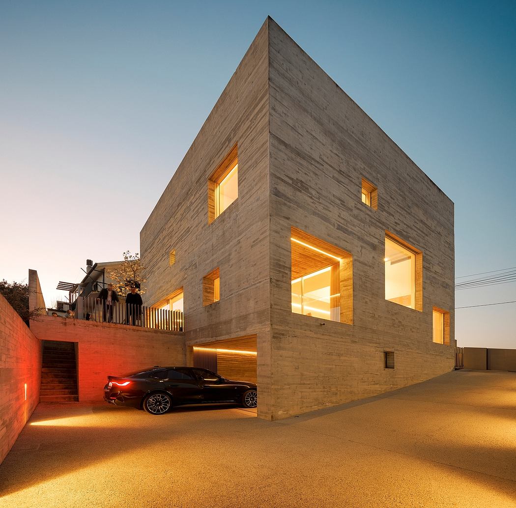 Modern concrete house illuminated at twilight with a car parked under.