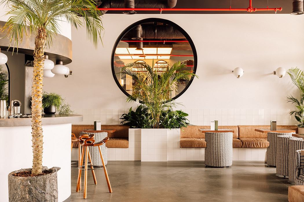 Modern cafe interior with potted plants, circular mirror, and mixed seating styles.