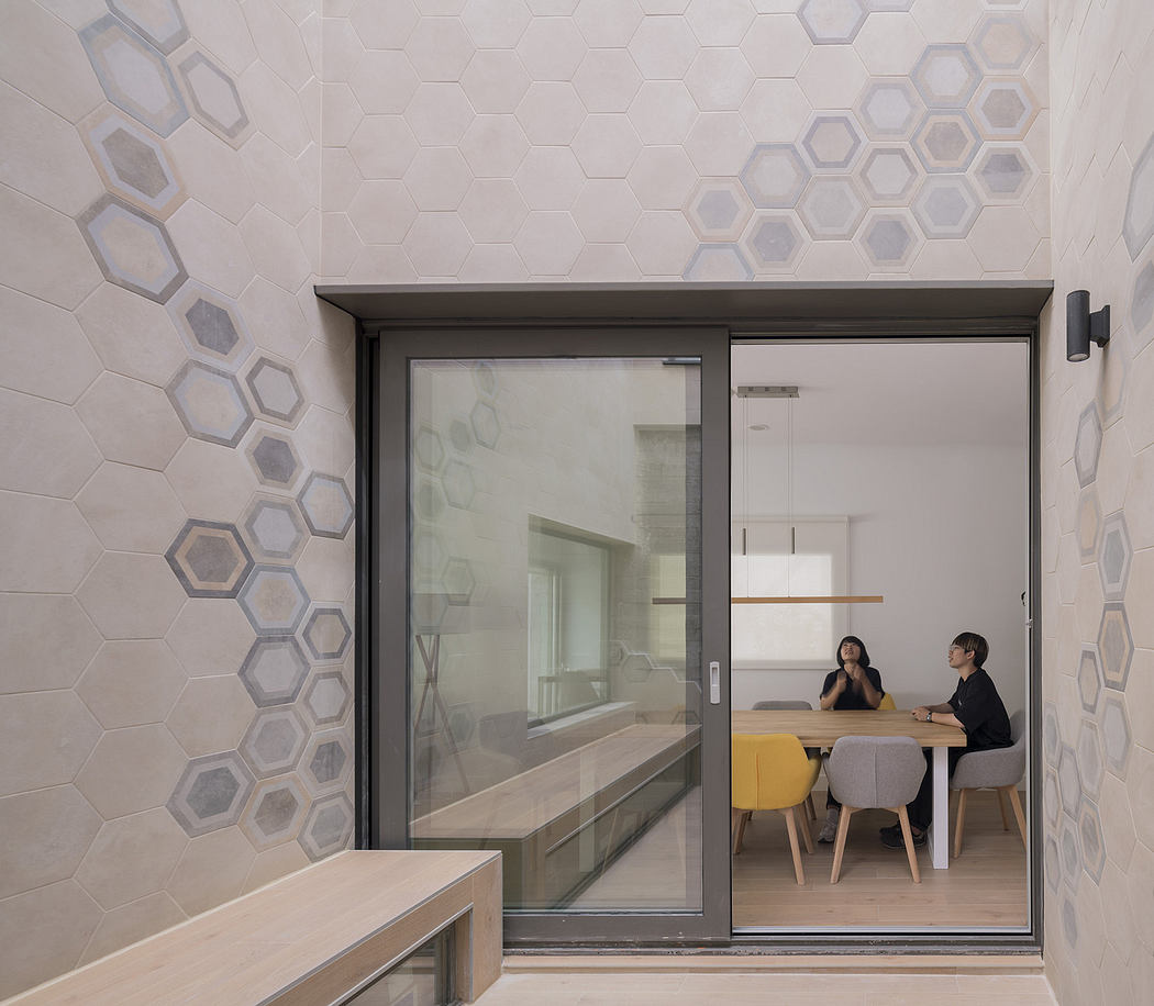 Modern room with hexagonal wall patterns, sliding door, and two people at a