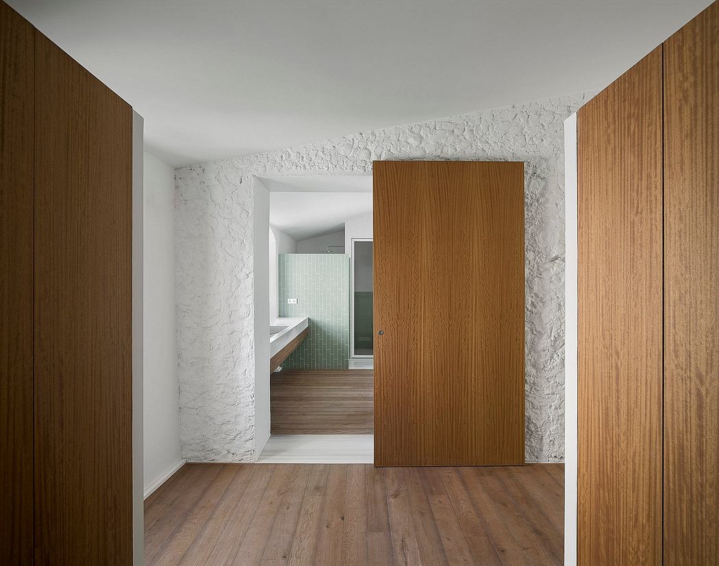 Minimalist interior with textured white walls and wooden doors.