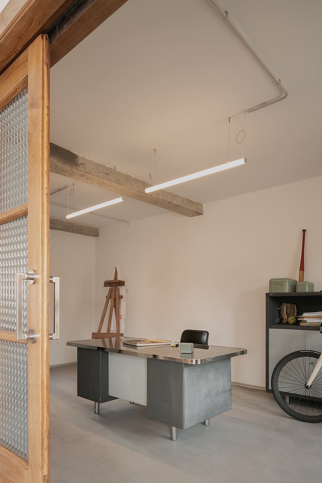 Minimalist home office with a desk, bookshelf, and bicycle storage.