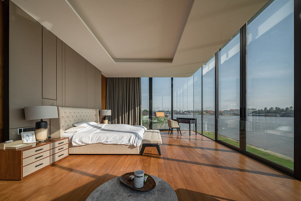 Modern bedroom with large windows overlooking a river.