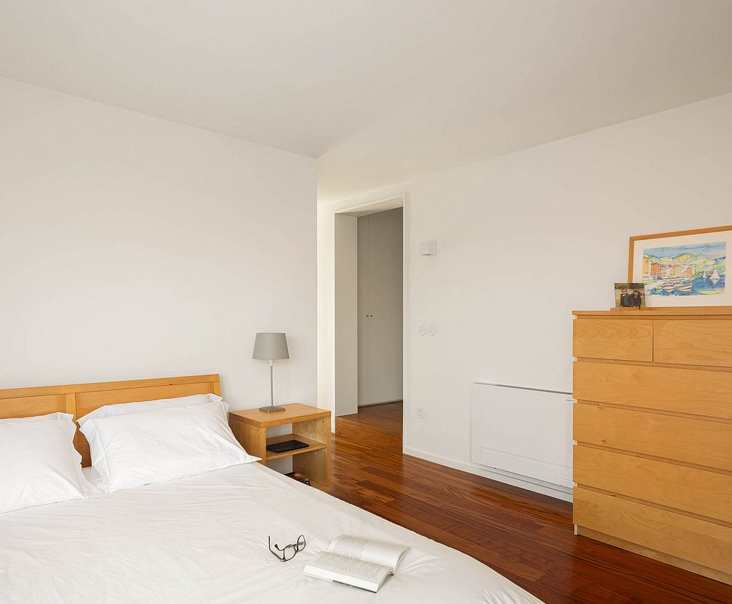 Minimalist bedroom with wooden flooring and simple furniture.