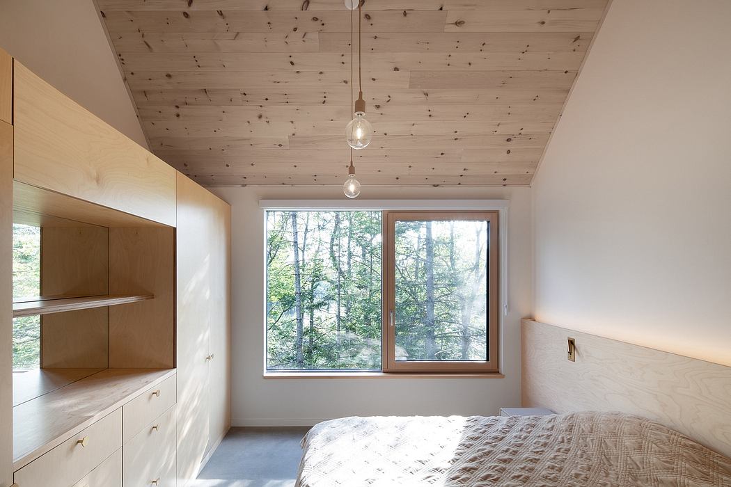 Minimalist bedroom with large window, wooden ceiling, and simple furnishings.