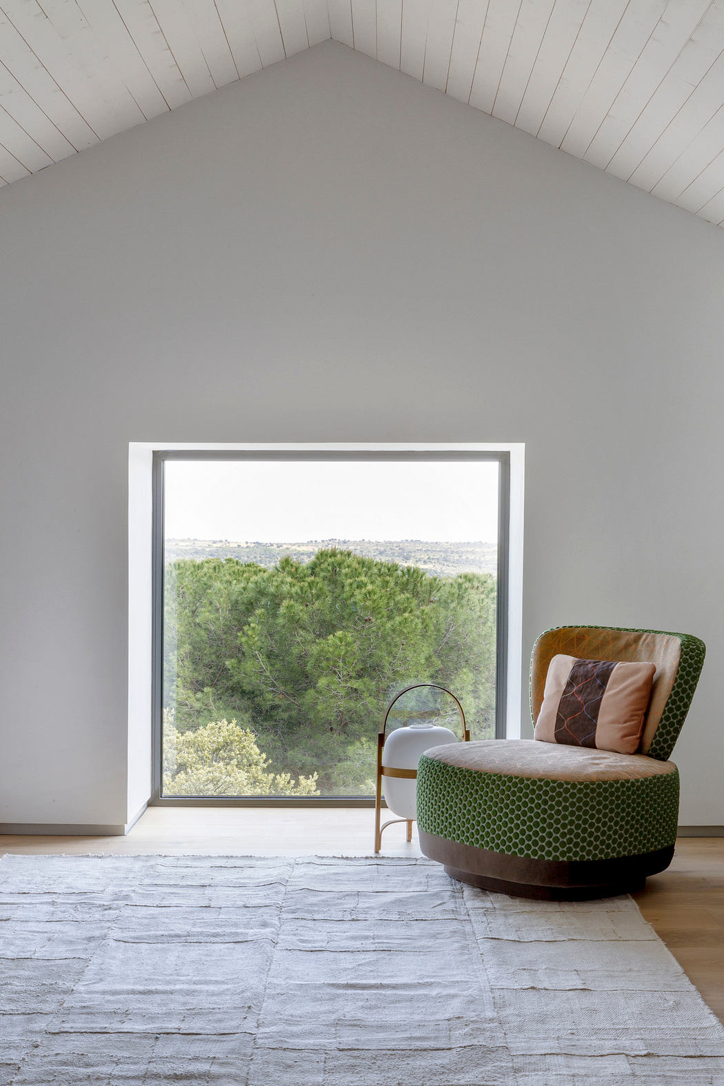 Minimalistic attic room with a large window and stylish armchair.