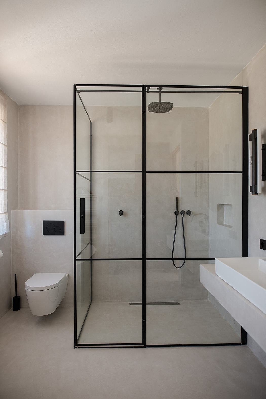 Minimalist bathroom with black-framed glass shower.