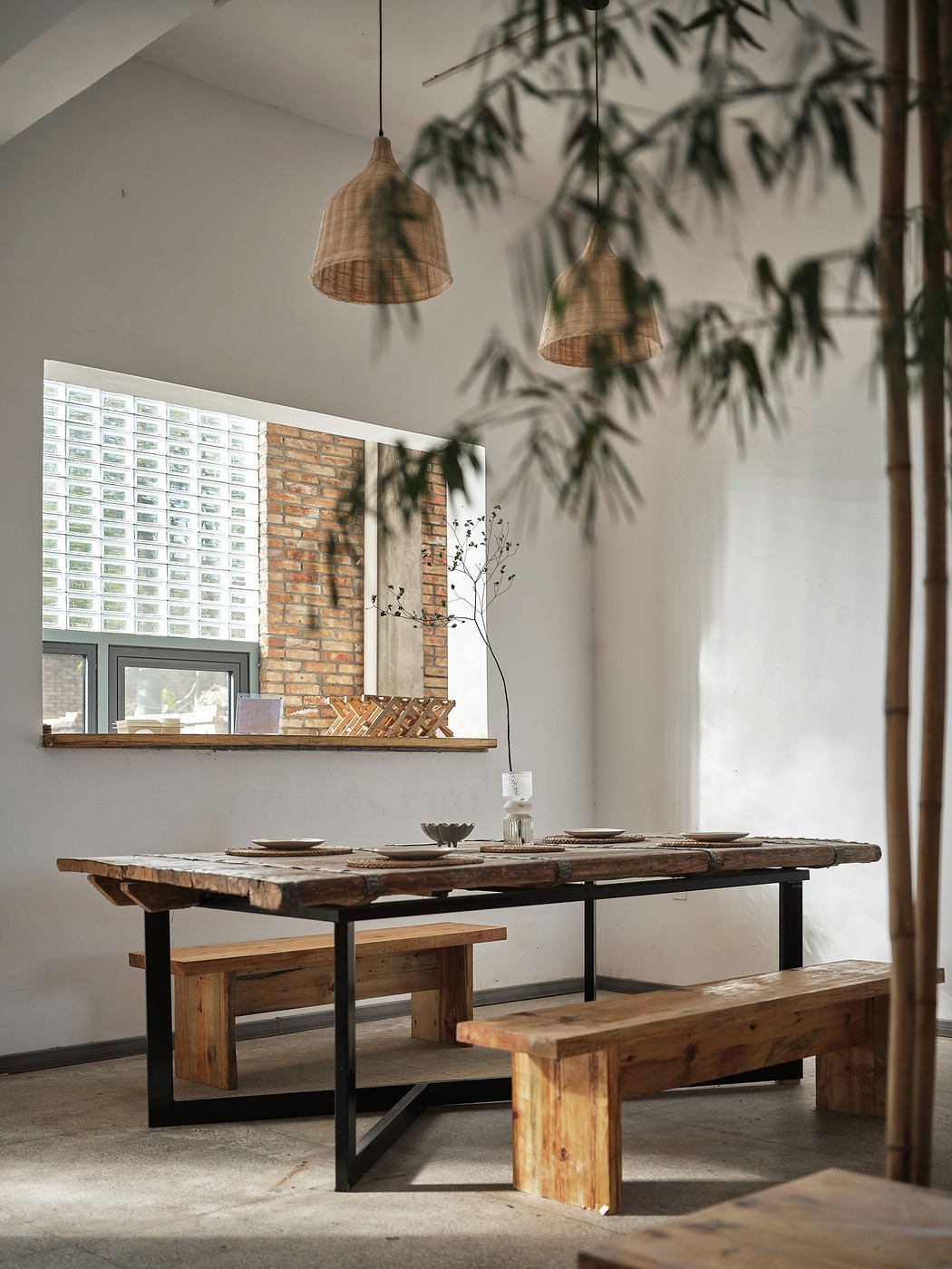 Minimalist dining room with wooden table, benches, and pendant lights.