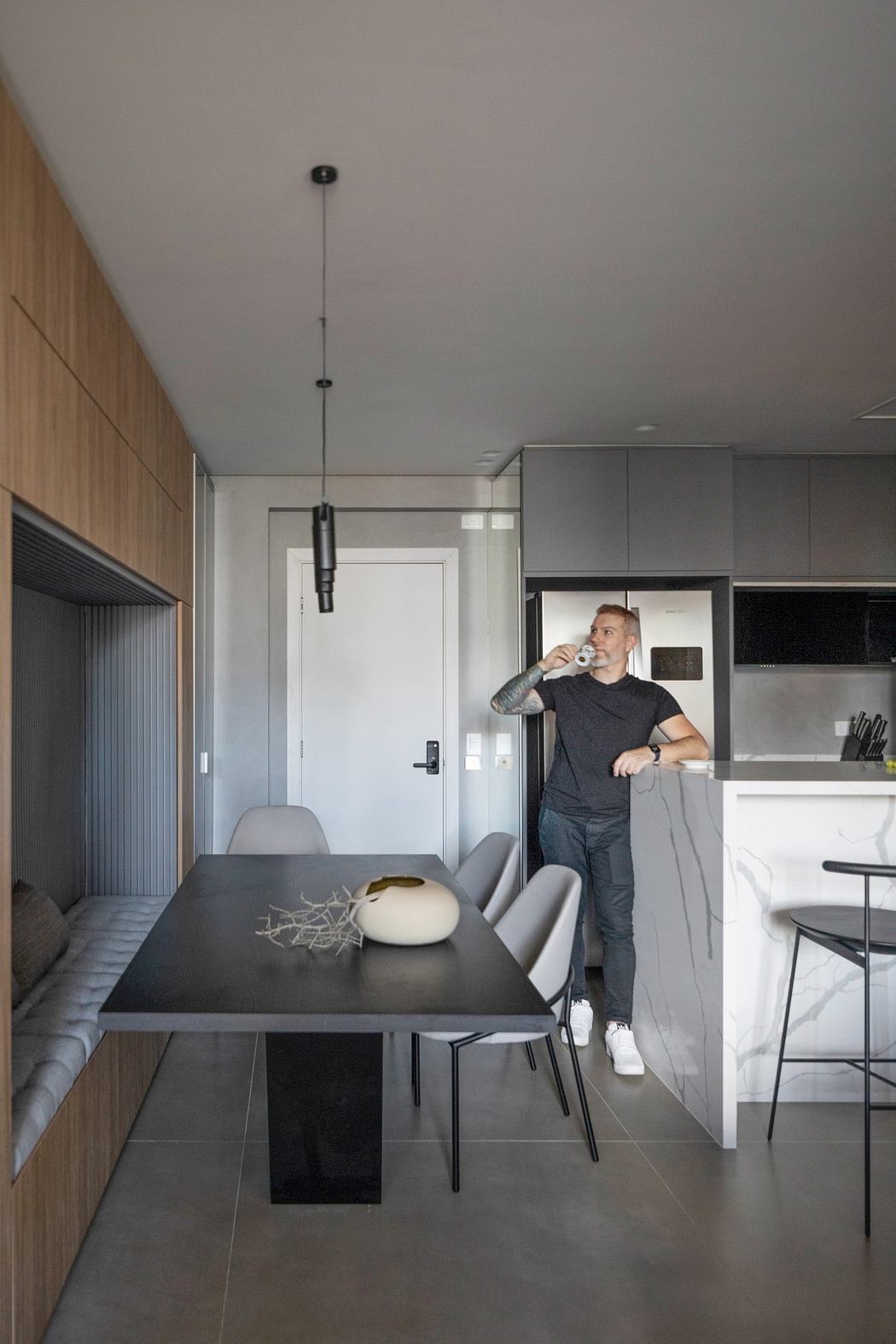 Man standing in a modern kitchen with dining area and minimalist decor.
