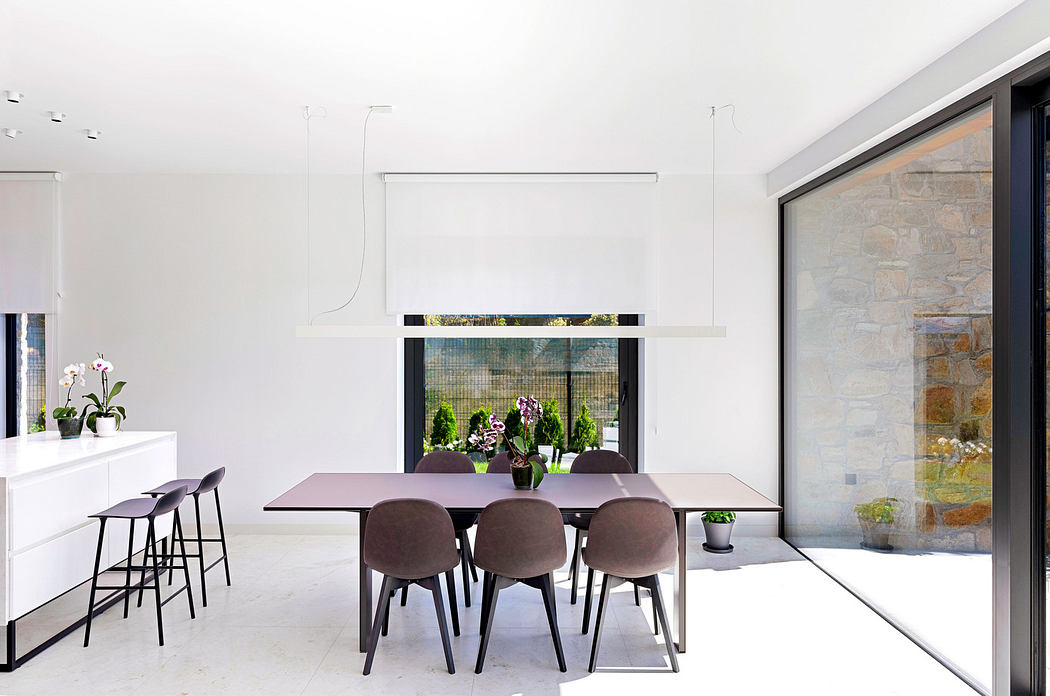 Modern dining room with white walls, a long table, and stone accent wall.