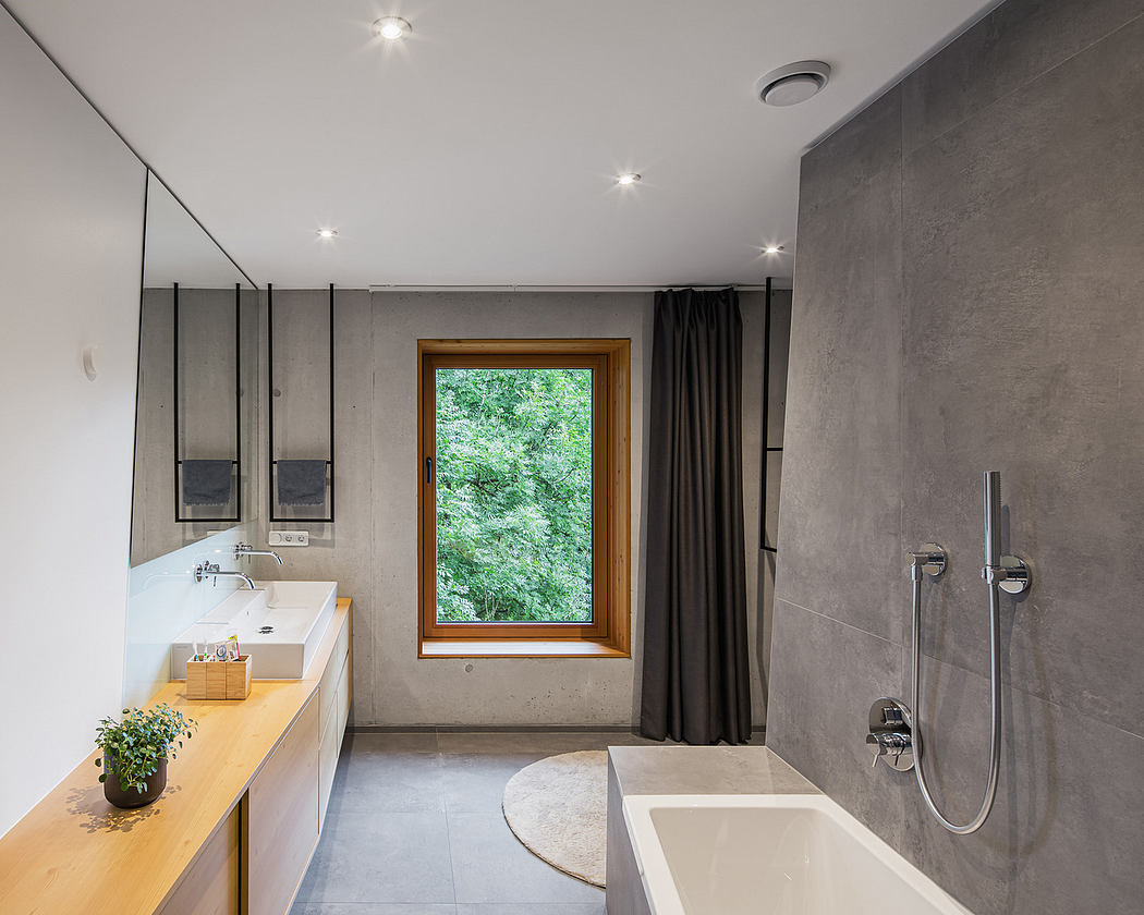 Modern bathroom with gray walls, wood accents, and a view of greenery through