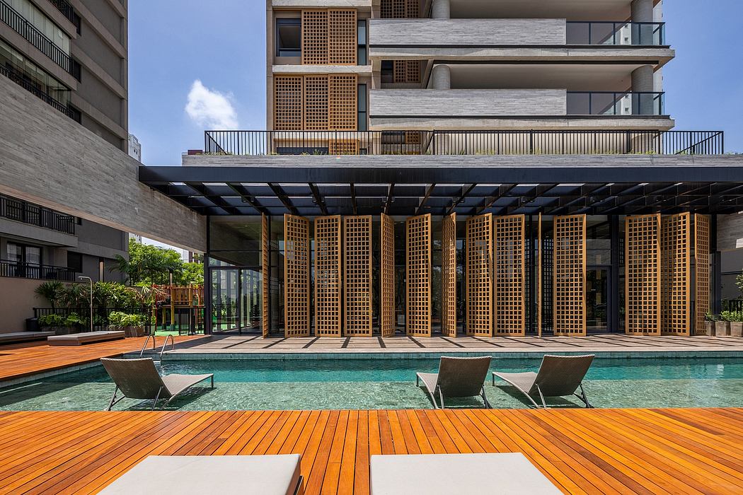 Modern poolside with wooden deck, sun loungers, and geometric building facade.