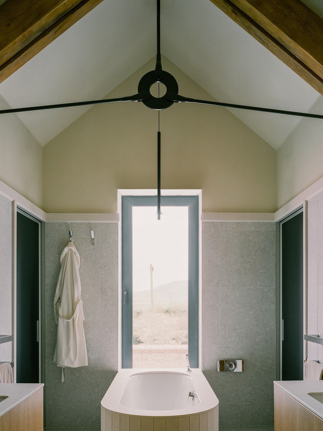 Minimalist bathroom with a vaulted ceiling and central window.