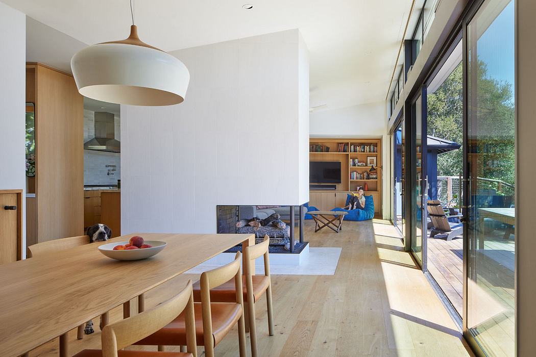 Modern dining room with wooden table, pendant light, and sliding glass doors leading to