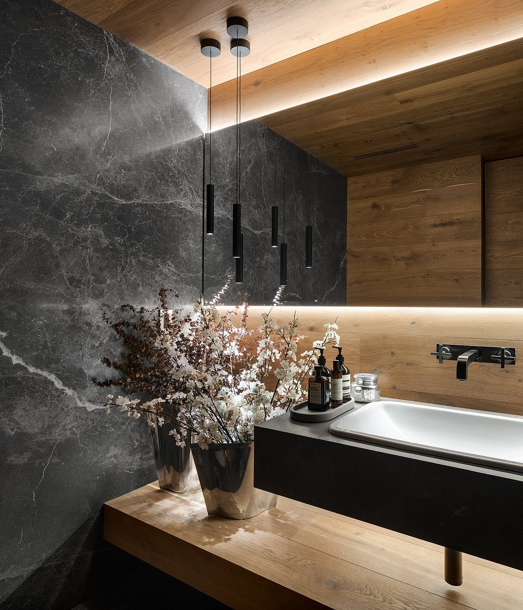 Modern bathroom with dark marble wall, wooden accents, and pendant lights.