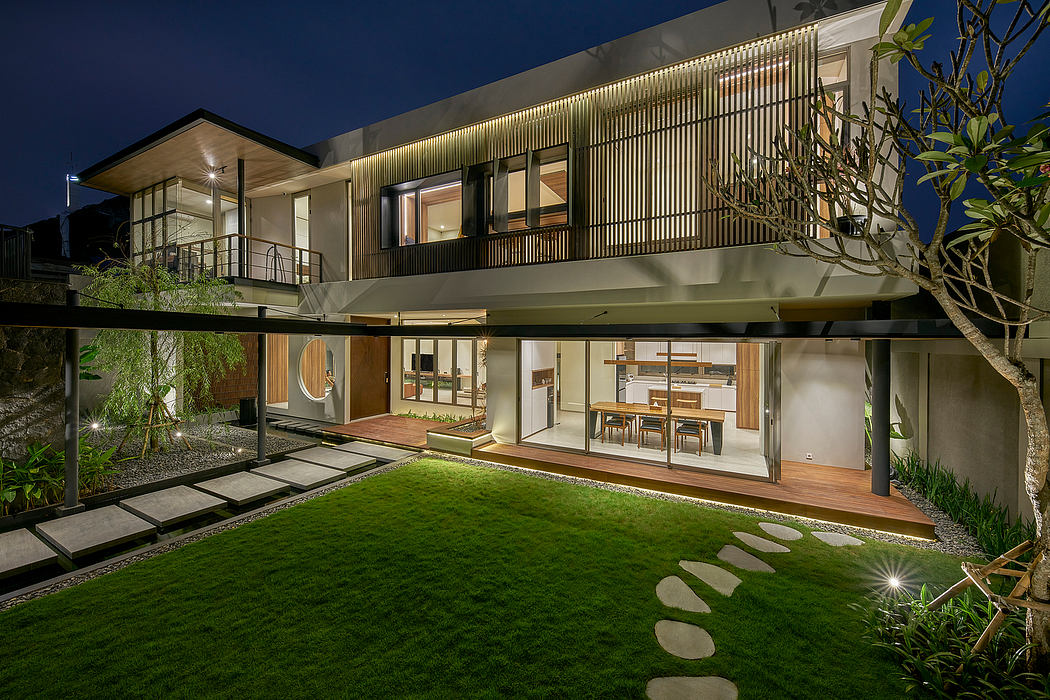 Modern two-story house with outdoor lighting and a landscaped garden at dusk.