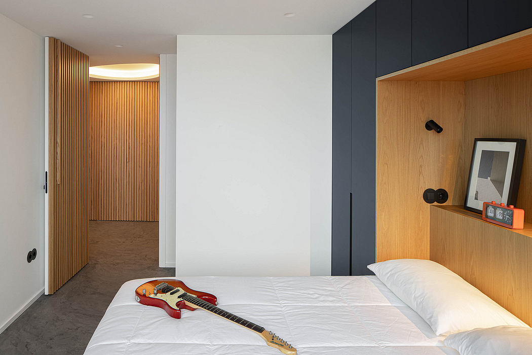 Modern bedroom with wooden wall paneling and a guitar on the bed.