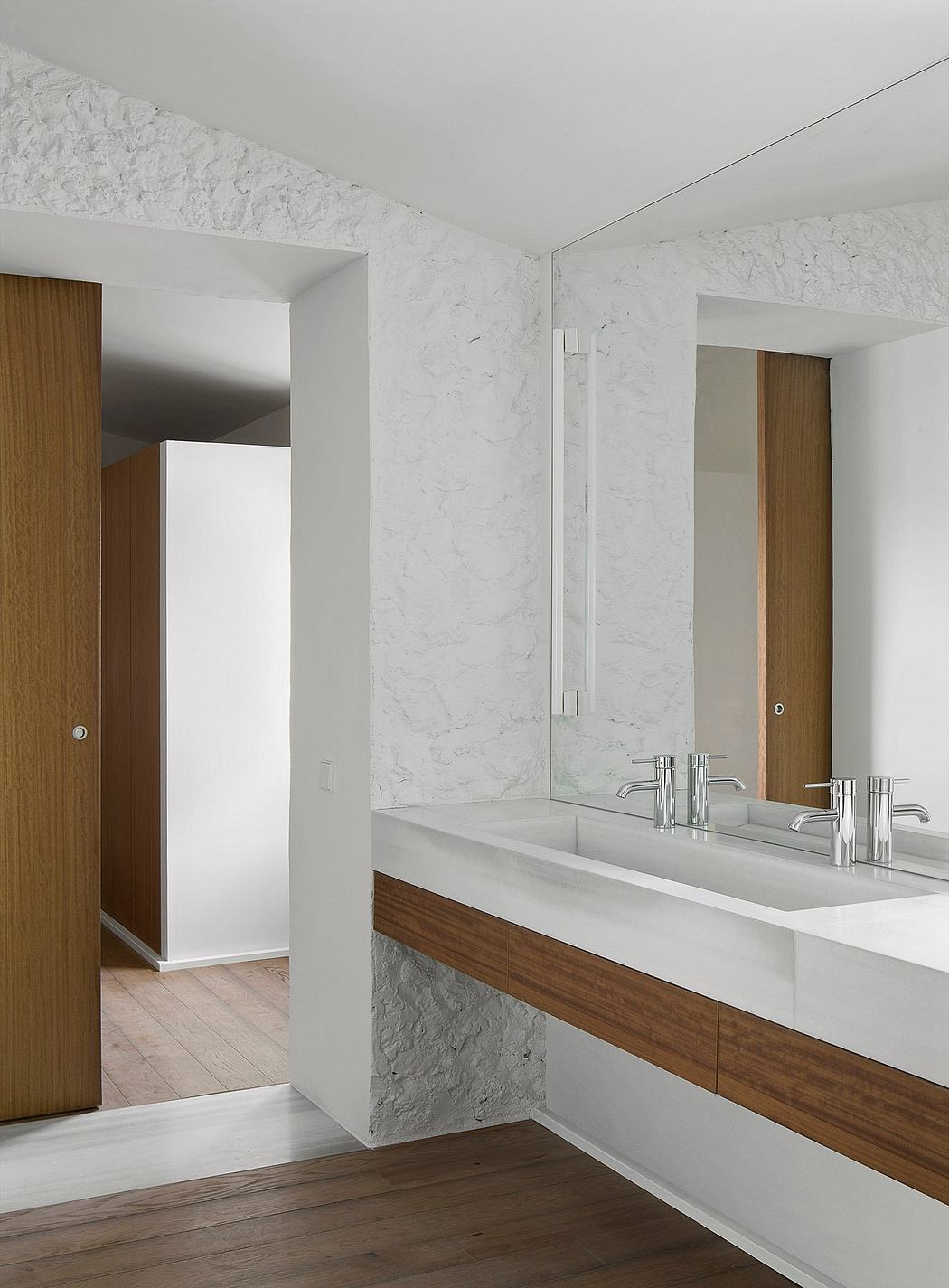 Contemporary bathroom with textured walls, wooden accents, and a sleek mirror.