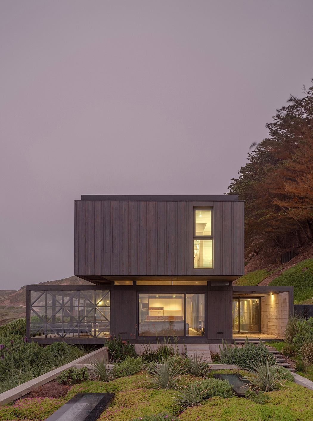 Contemporary two-story home with glass bridge against a twilight sky.