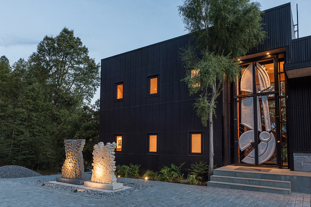 Contemporary black-clad building with unique circular door at dusk.