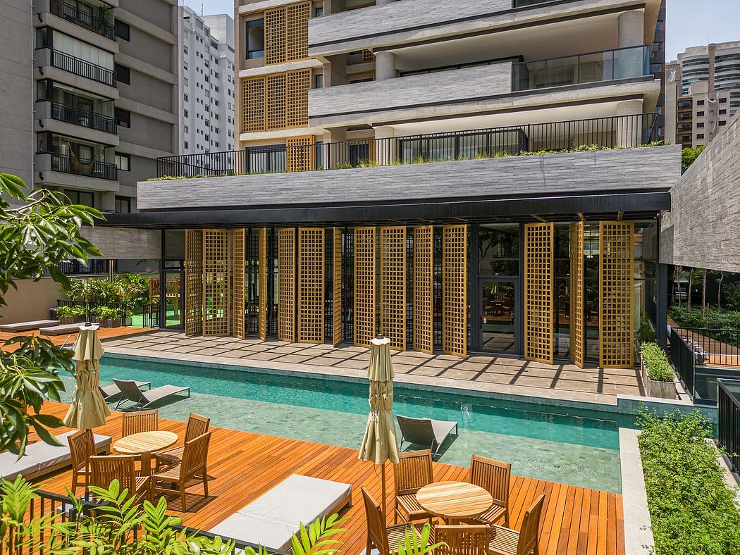 Modern apartment building with poolside wooden deck and lounging area.