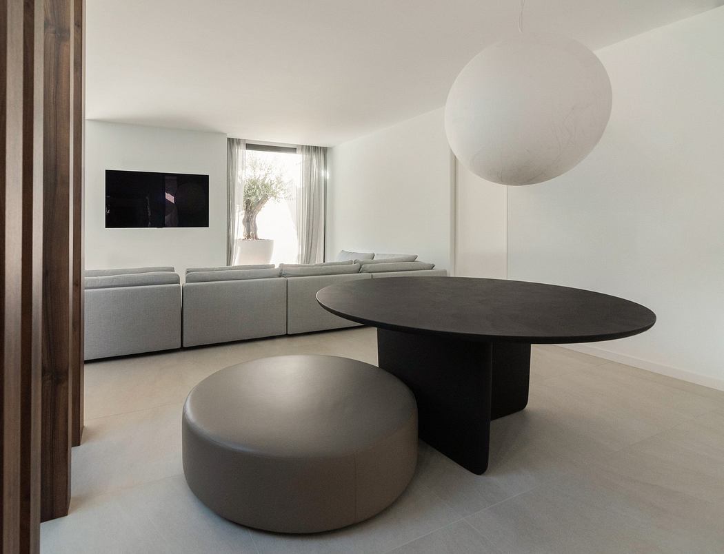 Minimalist living room with a round table, pouf, and modern sofa.