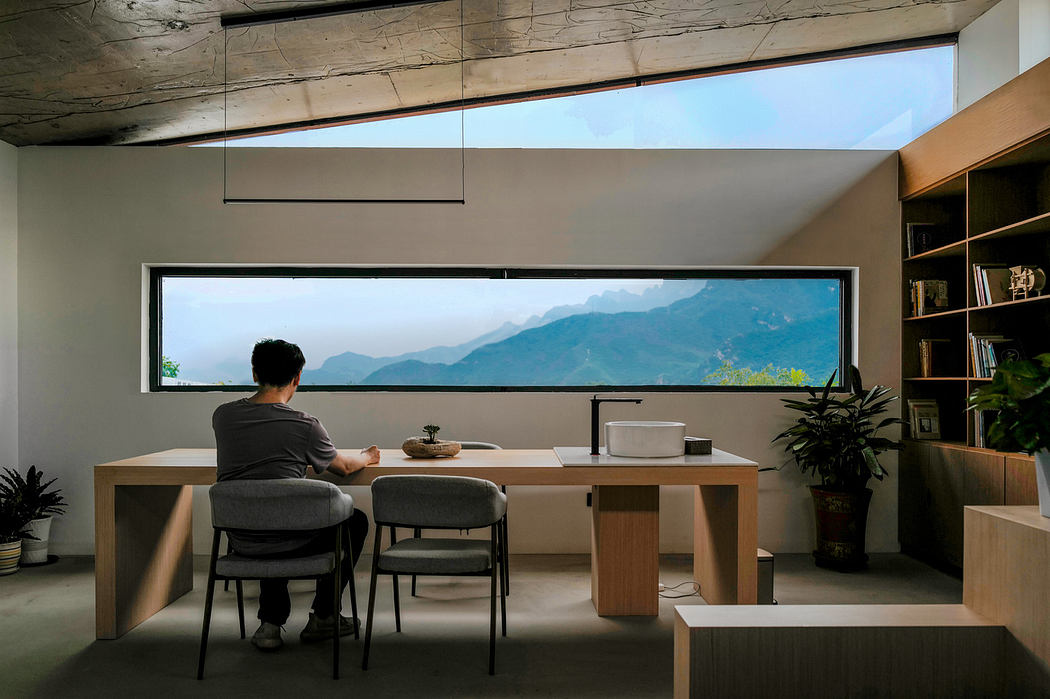 Person at a minimalist desk facing a large window with a mountain view in a modern