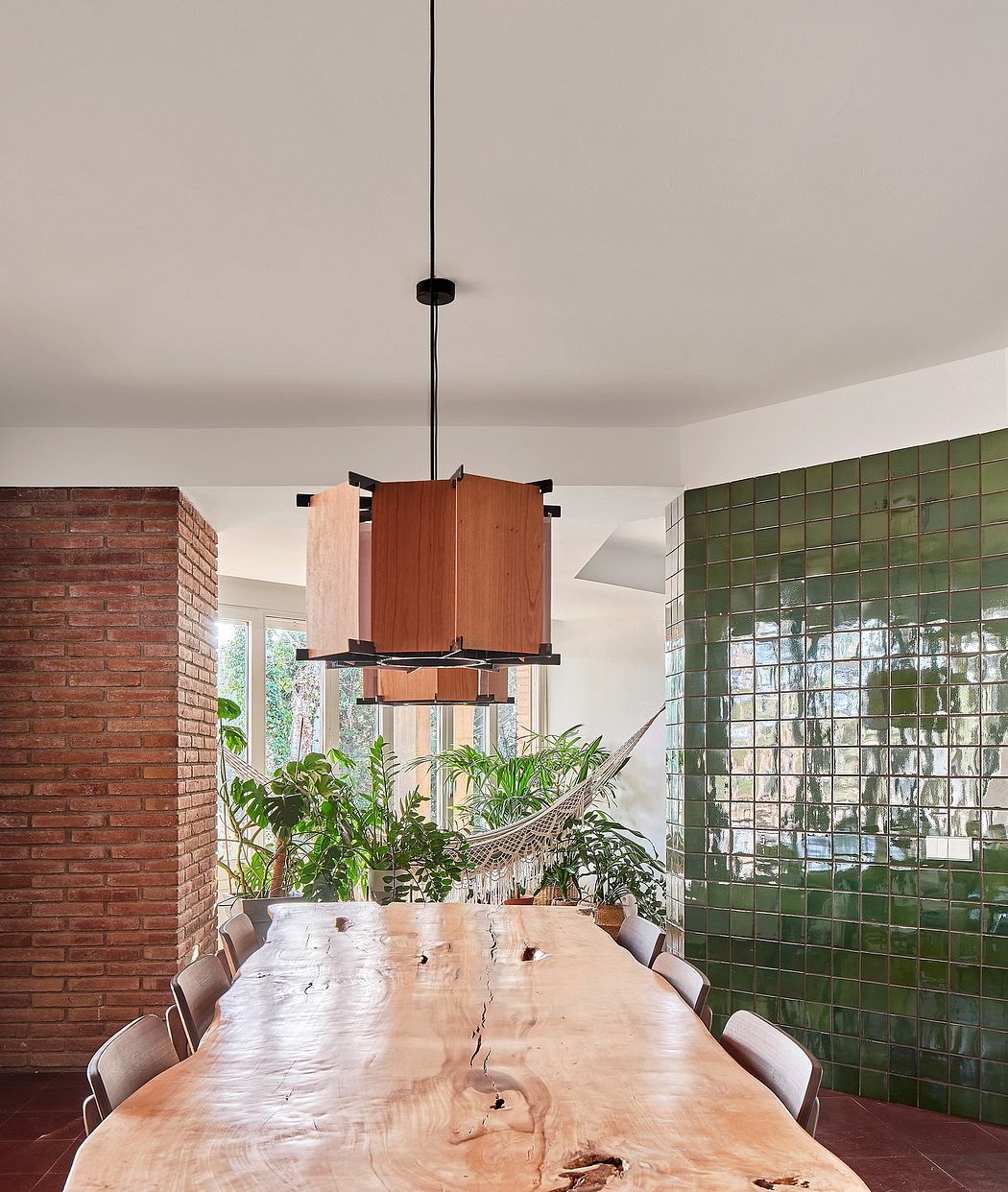 Contemporary dining area with a natural wood table and green glass block wall.