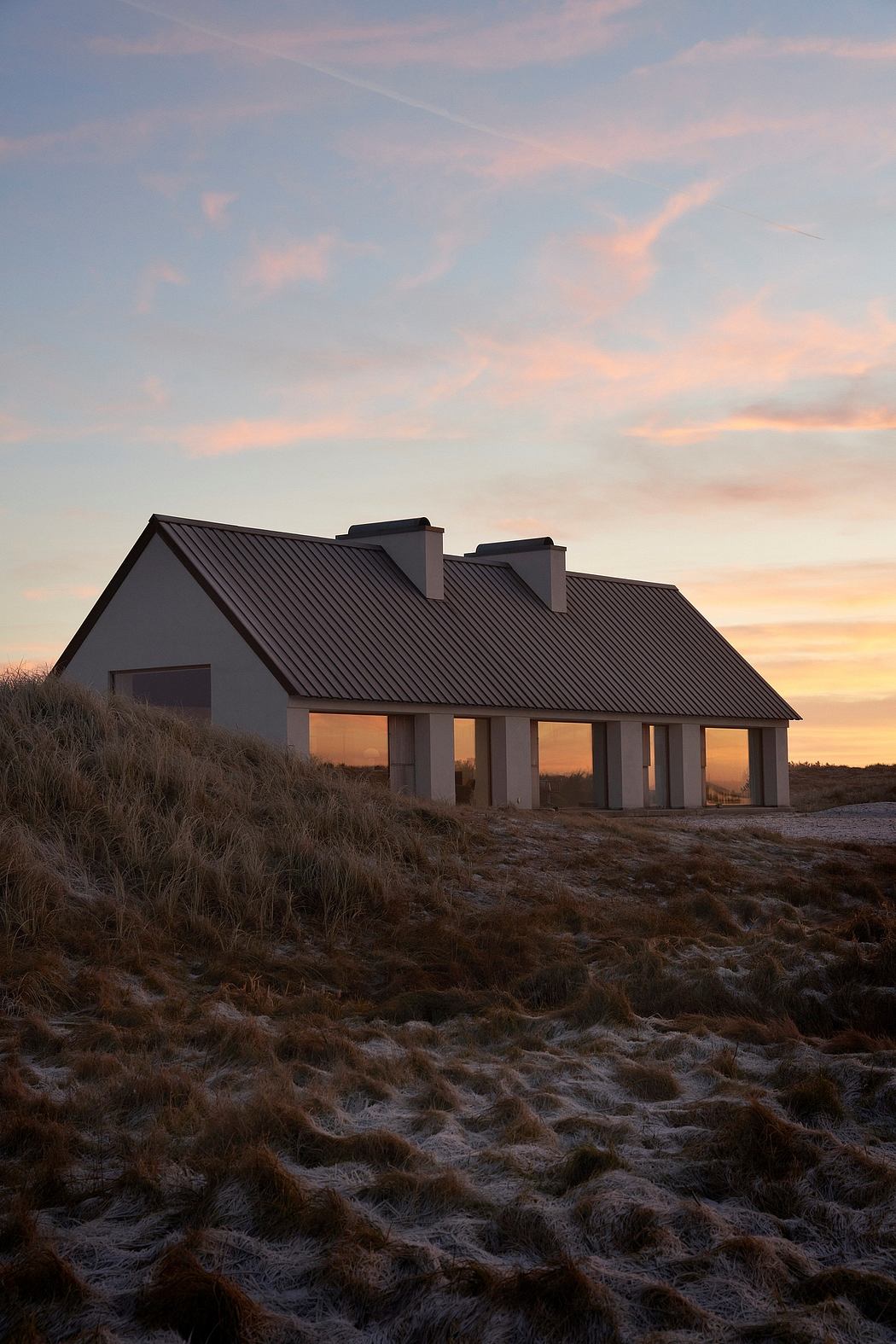 Contemporary house amidst dunes at sunset.