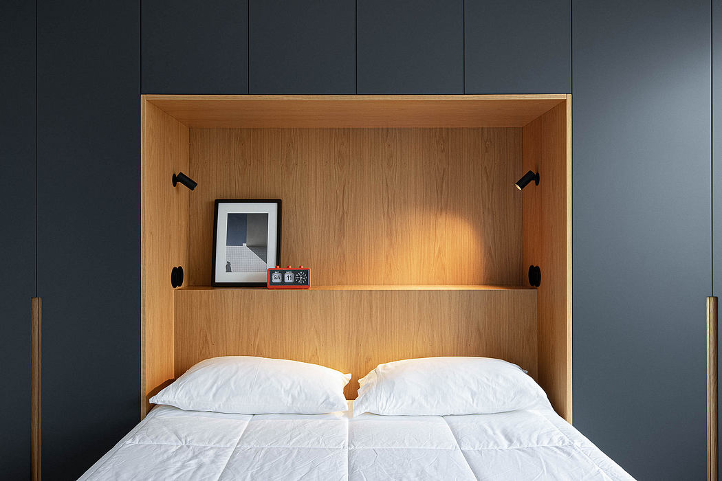 Modern bed with wooden headboard niche, white bedding, and dark walls.